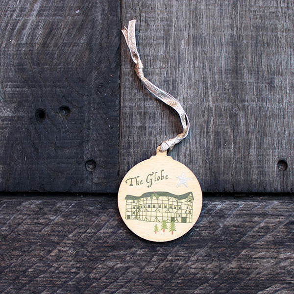 Green round wooden decoration with 'The Globe' and stylised drawing of the Globe Theatre on wooden background