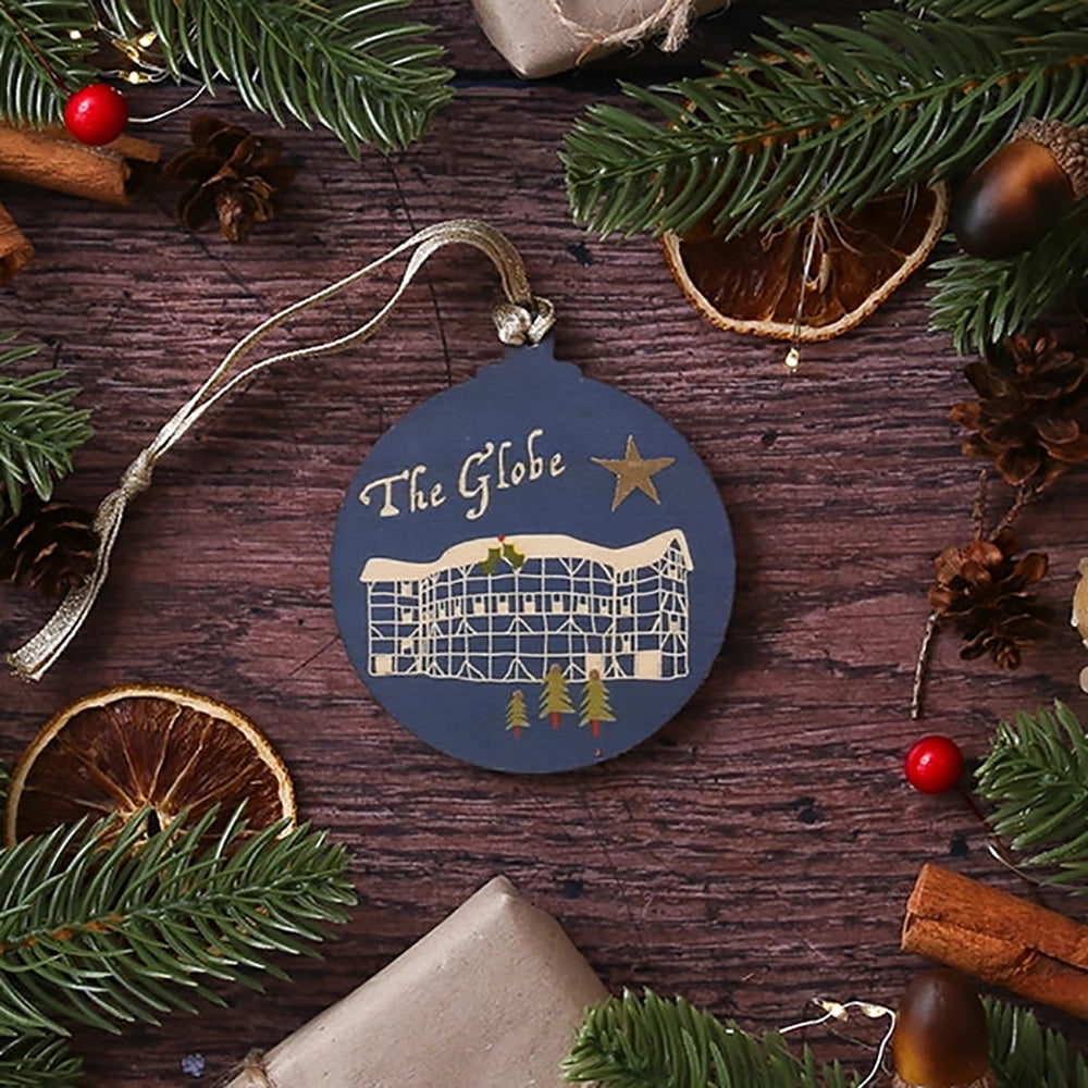 Blue round wooden decoration with 'The Globe' and stylised drawing of the Globe Theatre on wooden background with Christmas greenery
