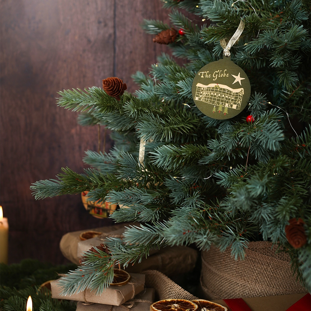Green round wooden decoration with 'The Globe' and stylised drawing of the Globe Theatre on wooden background with Christmas greenery