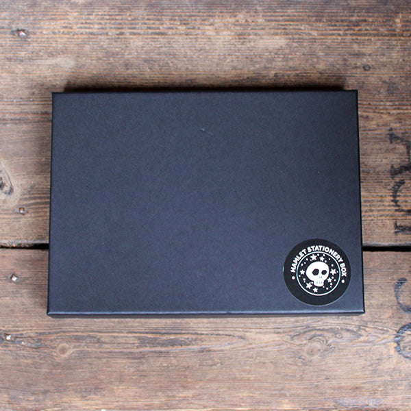 A black gift box with a black and white sticker in the bottom right corner
