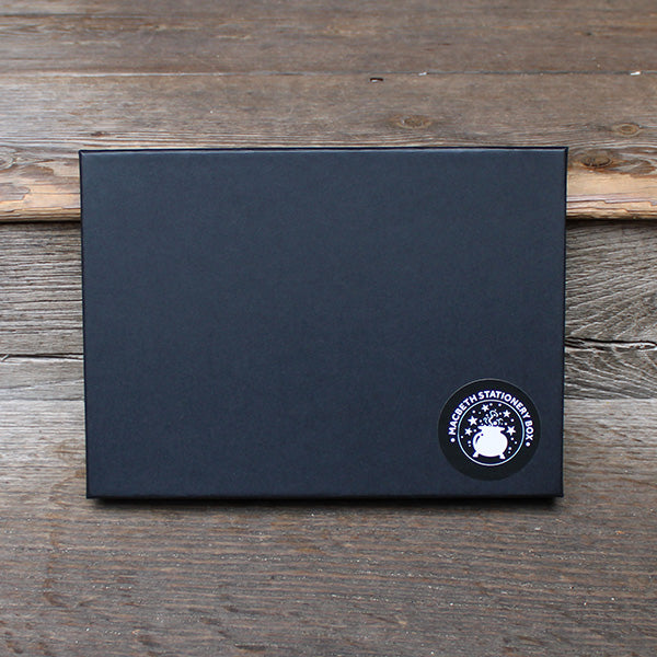A black gift box with a black and white sticker in the bottom right corner
