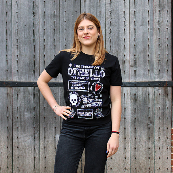 Black t-shirt with white graphic text all over the front with doodles of skulls, hearts and leaves