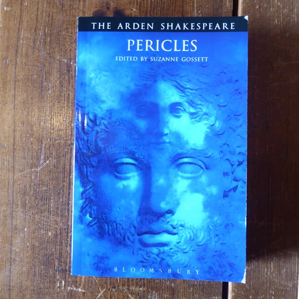 Royal blue paperback book with distorted images of 2 stone faces on cover, with white text