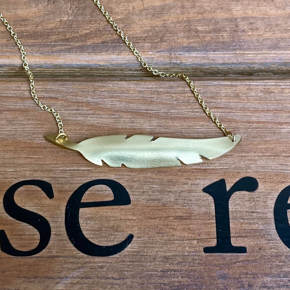 brass metal quill shaped necklace with a gold coloured chain