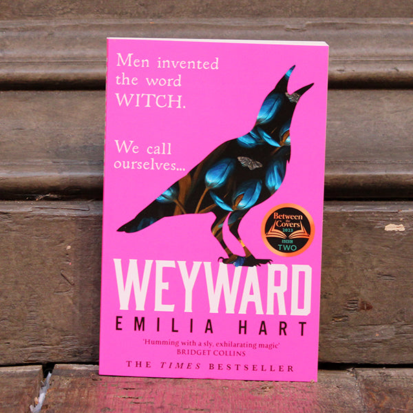 Hot pink paperback book with image of a crow that appears made of flowers
