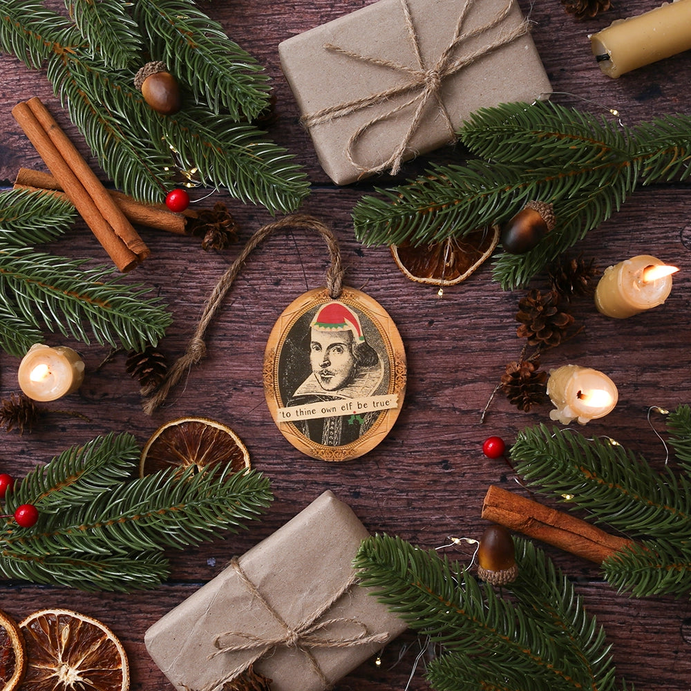 Wooden oval decoration with black portrait and cartoon red santa hat, on wooden background with Christmas greenery