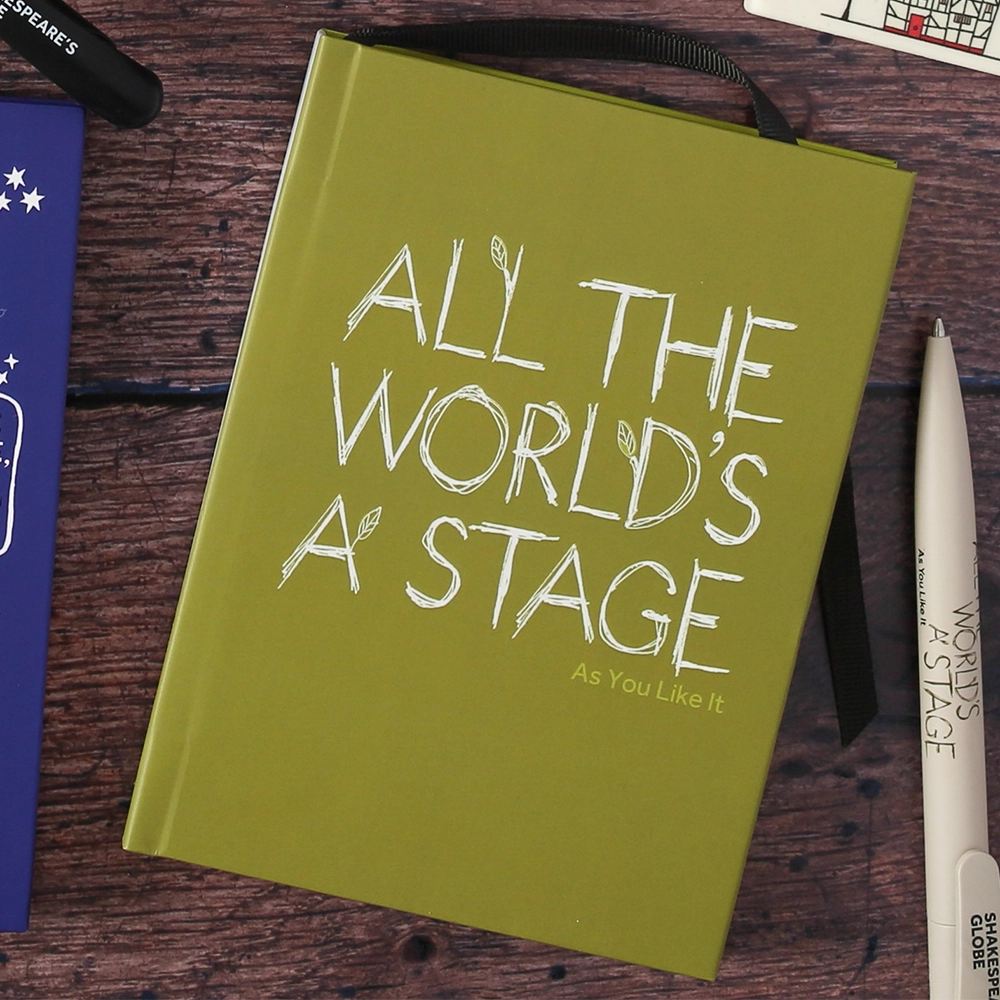 Sage green hardback journal with a quote from Shakespeare play, As You Like It (All the world's a stage) printed in white on the cover. The lettering is hand-drawn in a scribble style and has small lime green leaves growing out of it.