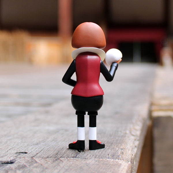plastic figure of Shakespeare wearing a black and deep red costume holding a white skull and feather