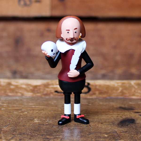 plastic figure of Shakespeare wearing a black and deep red costume holding a white skull and feather