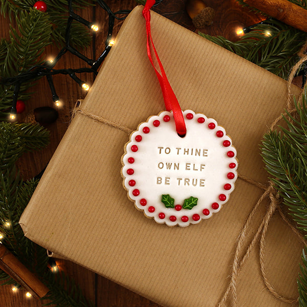 Decorative biscuit with text on a wrapped gift with Christmas tree background