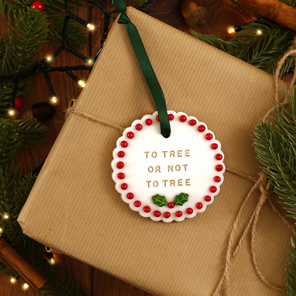 Christmas biscuit on a wrapped present with 'To Tree or Not to Tree' text, surrounded by festive decorations.
