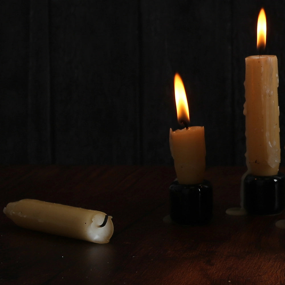 3 beeswax candles, 2 on the left are lit, the one on the right is lying down, unlit