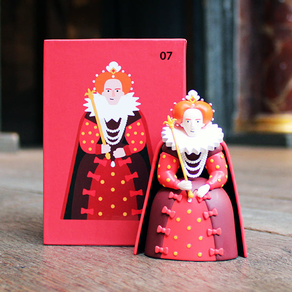 Red figurine of a character with a red box on a wooden surface.