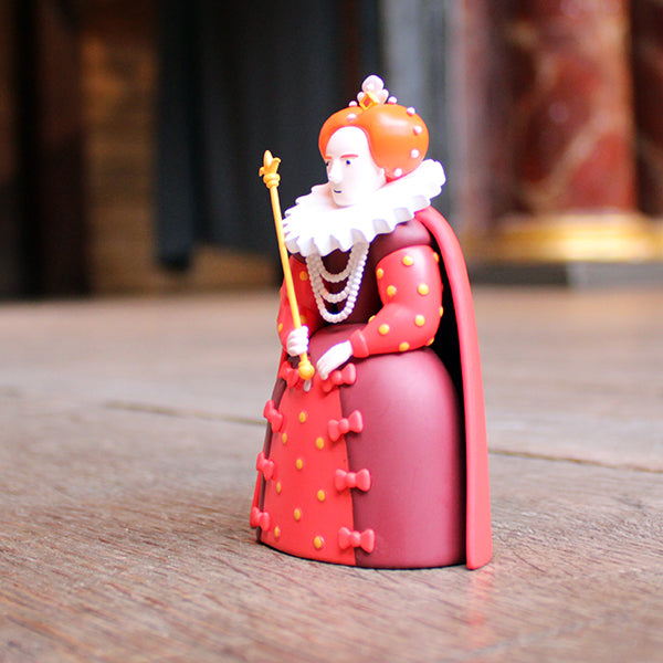 Figurine of a character in a red outfit with a crown and staff on a wooden surface