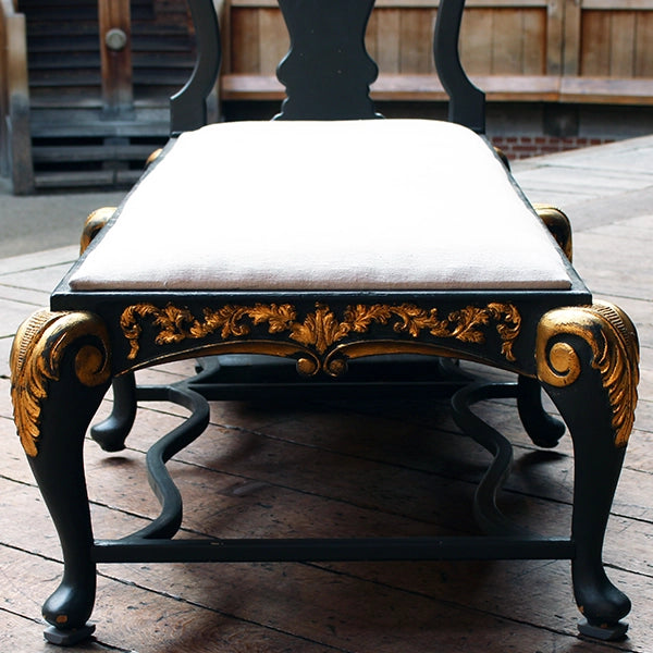Matt grey with gold leaf detailing chaise long with white cheesecloth upholstery, sitting on wood panel stage