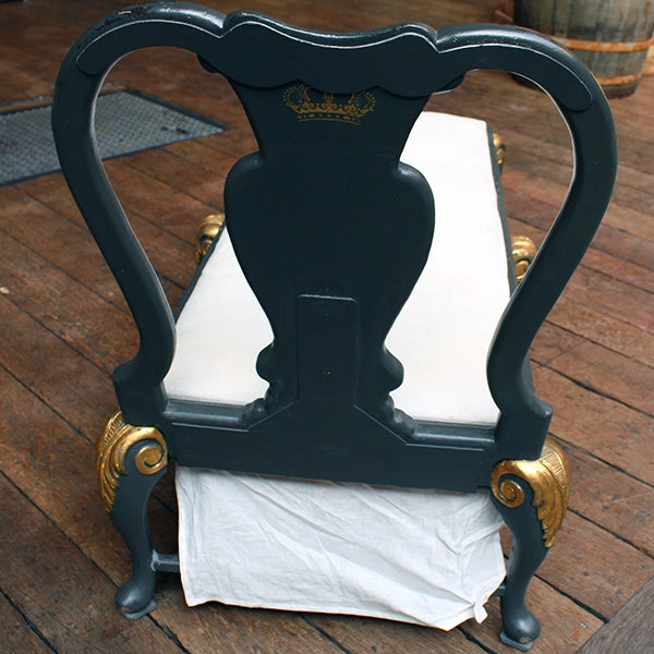 Matt grey with gold leaf detailing chaise long with white cheesecloth upholstery, sitting on wood panel stage