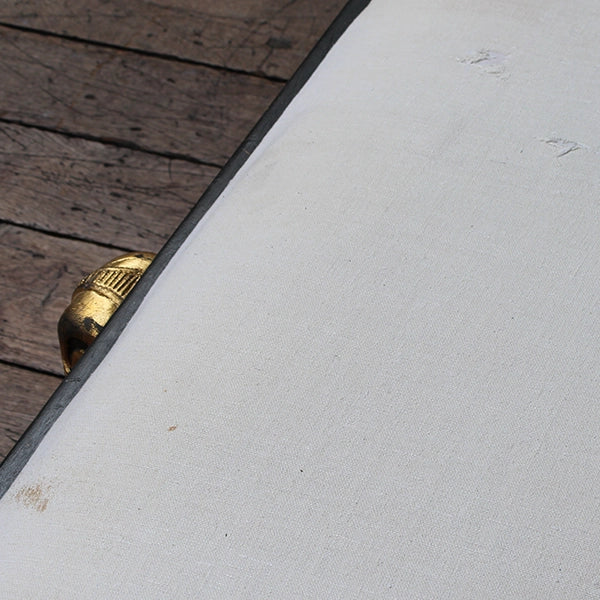 Matt grey with gold leaf detailing chaise long with white cheesecloth upholstery, sitting on wood panel stage