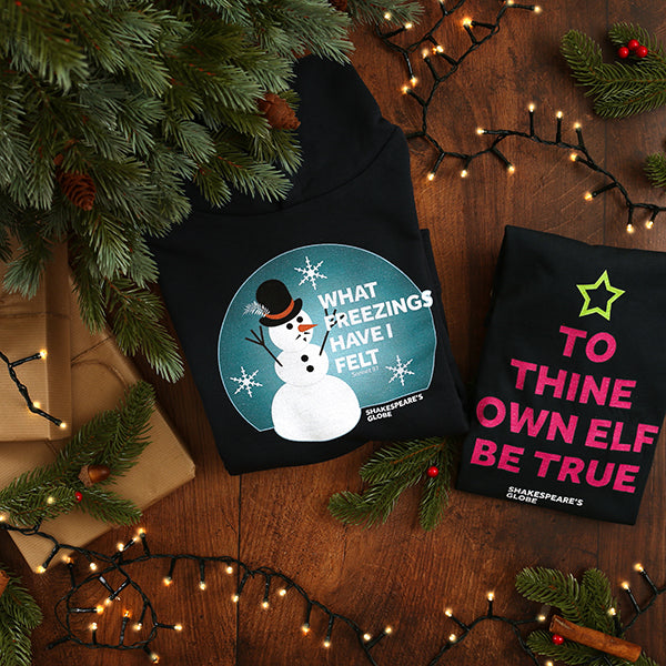 Two garments with festive designs on a wooden surface with Christmas decorations.