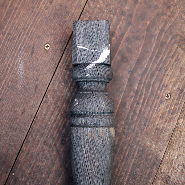 Wooden baluster with a textured surface on a wooden floor