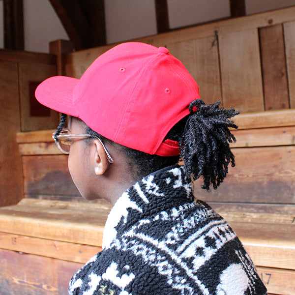 Red cotton baseball cap with curved bill and Velcro back closure.