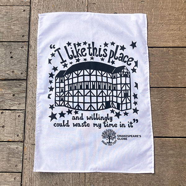 White tea towel with black text and graphic on a wooden surface