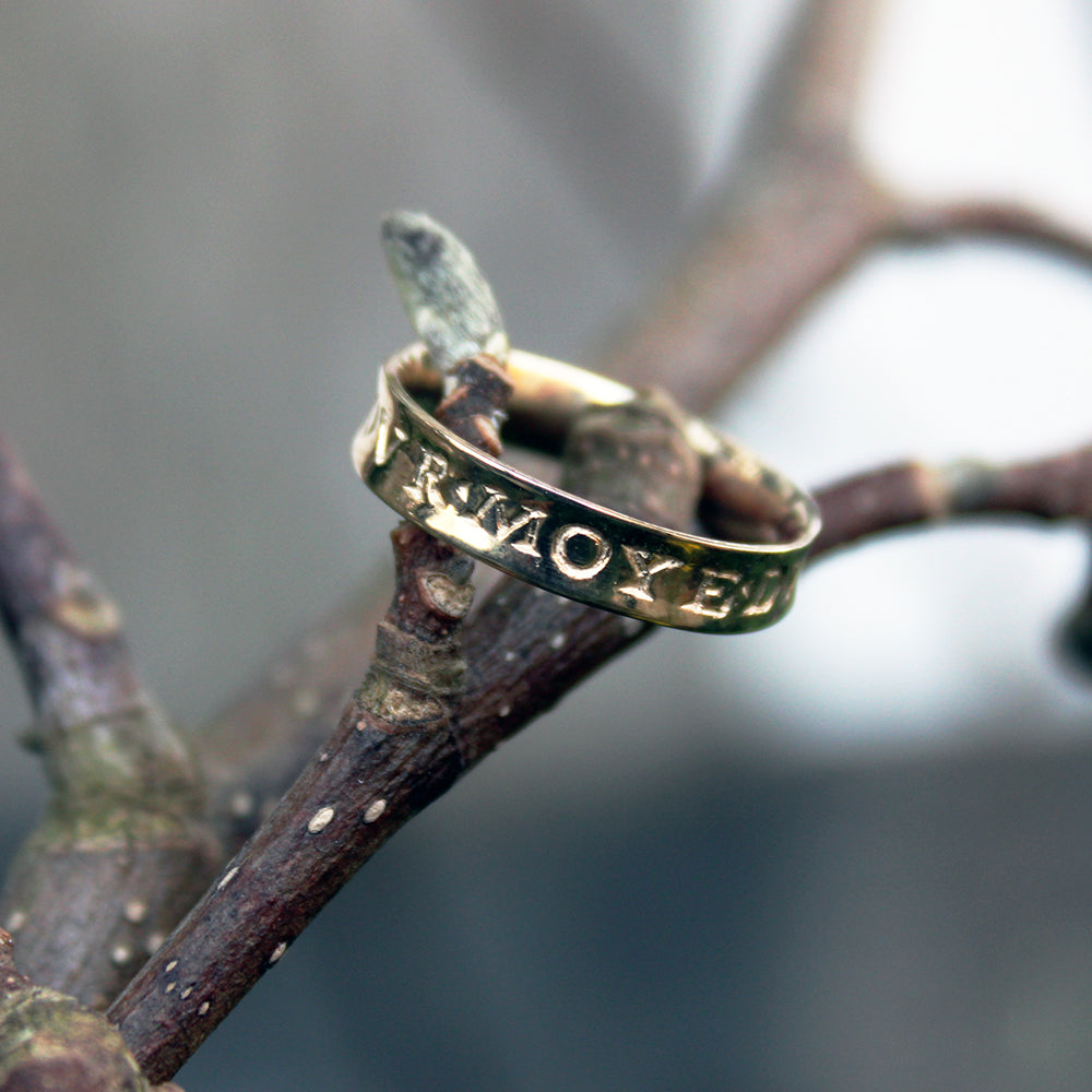Gold ring with engraved letters on a wooden twig