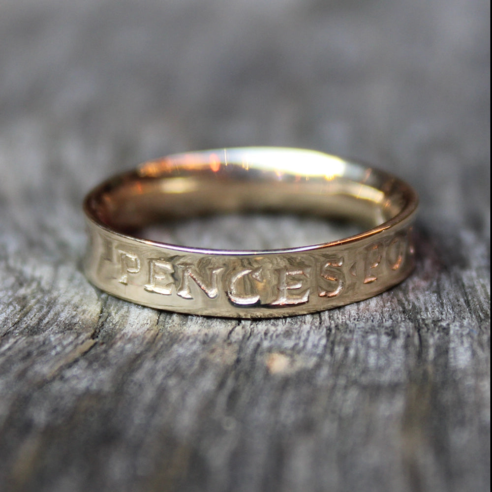 a gold ring with engraved letters on a wooden background