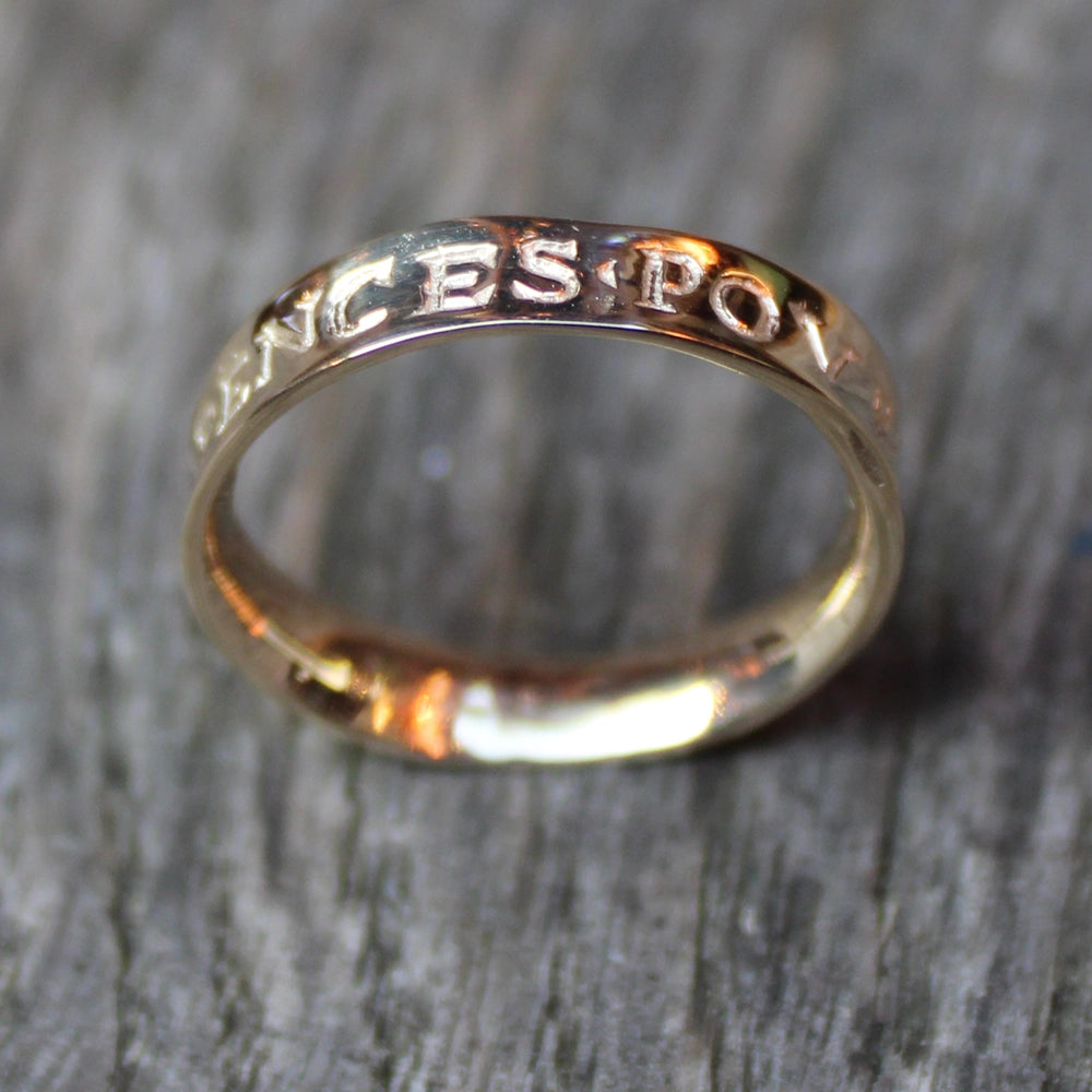 a gold ring with engraved letters on a wooden background