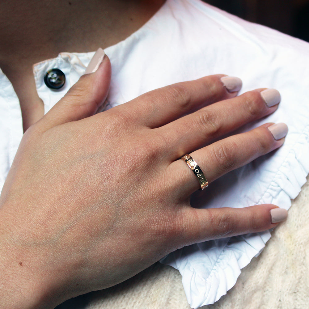 a hand wearing a gold ring resting on a white collar