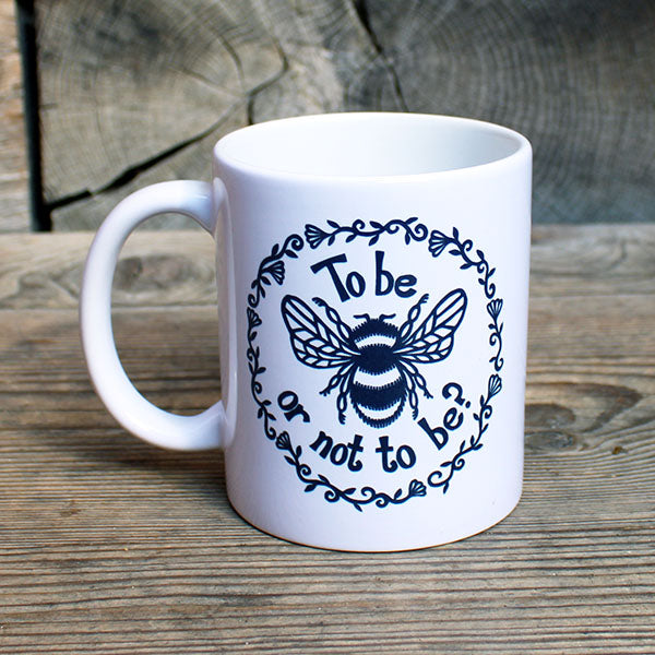 white ceramic mug with a black print of a bee and a quote