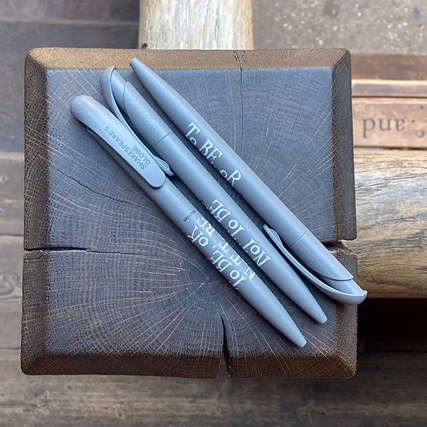 Three grey pens on a wooden surface