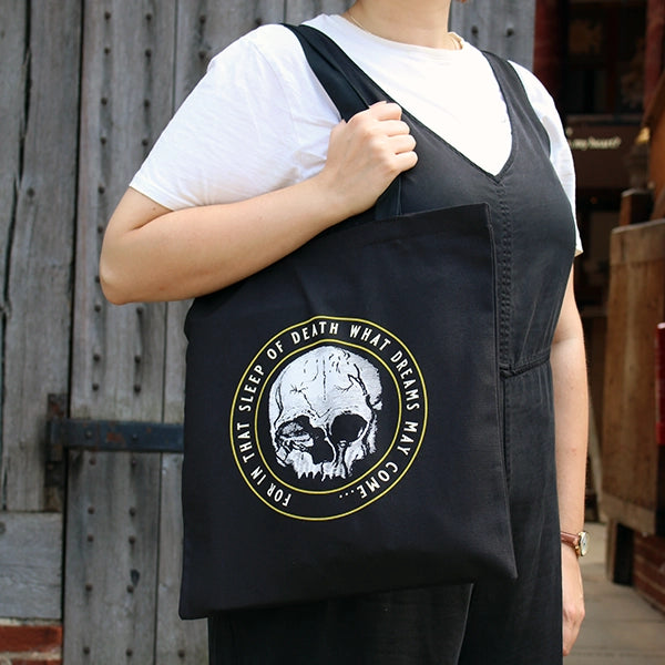 Black cotton two handle tote bag with circular graphic of skull with surrounding text