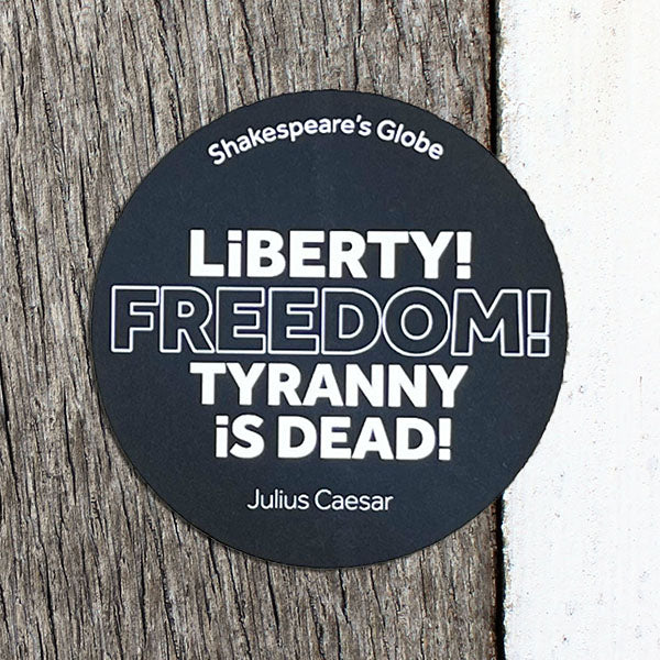 Round black sticker with white text on a wooden surface
