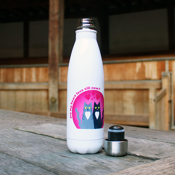 White insulated bottle with a cat design and text on a wooden surface