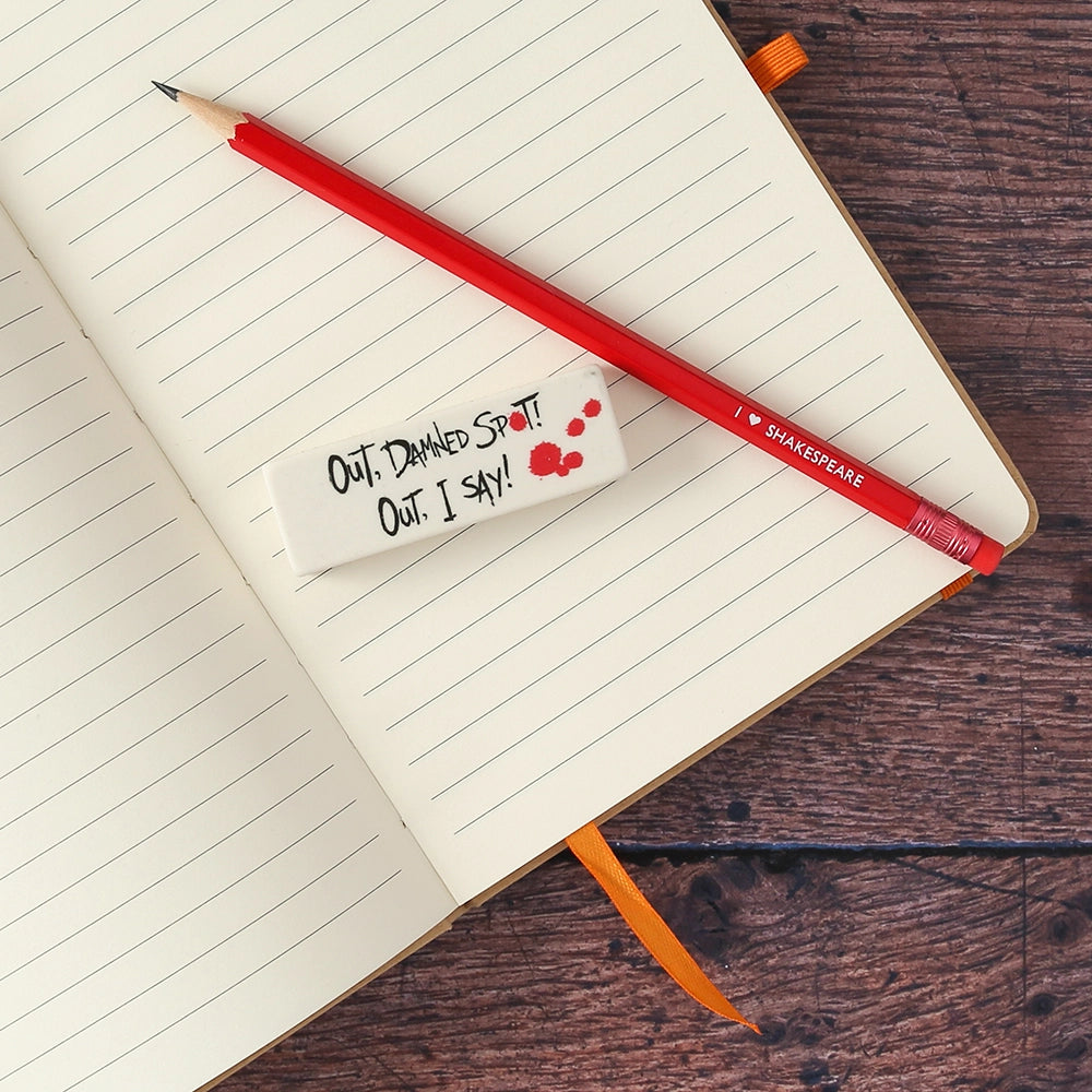 White eraser with black text and red pencil on open notebookRed pencil with red eraser and white stamped text with white eraser on open lined notebook
