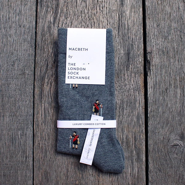 Marled grey cotton blend socks with repeating pattern Macbeth approximately 1 inch apart, with white card packaging