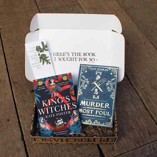 Two blue paperback books in open card box, with white card bookmark, on wooden stage