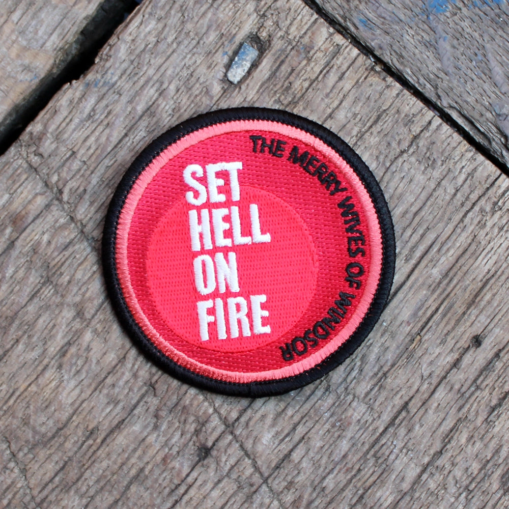 Red and black round embroidered patch on a wooden floor