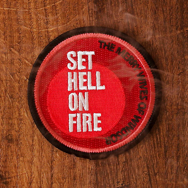 Red and black round embroidered patch on a wooden background