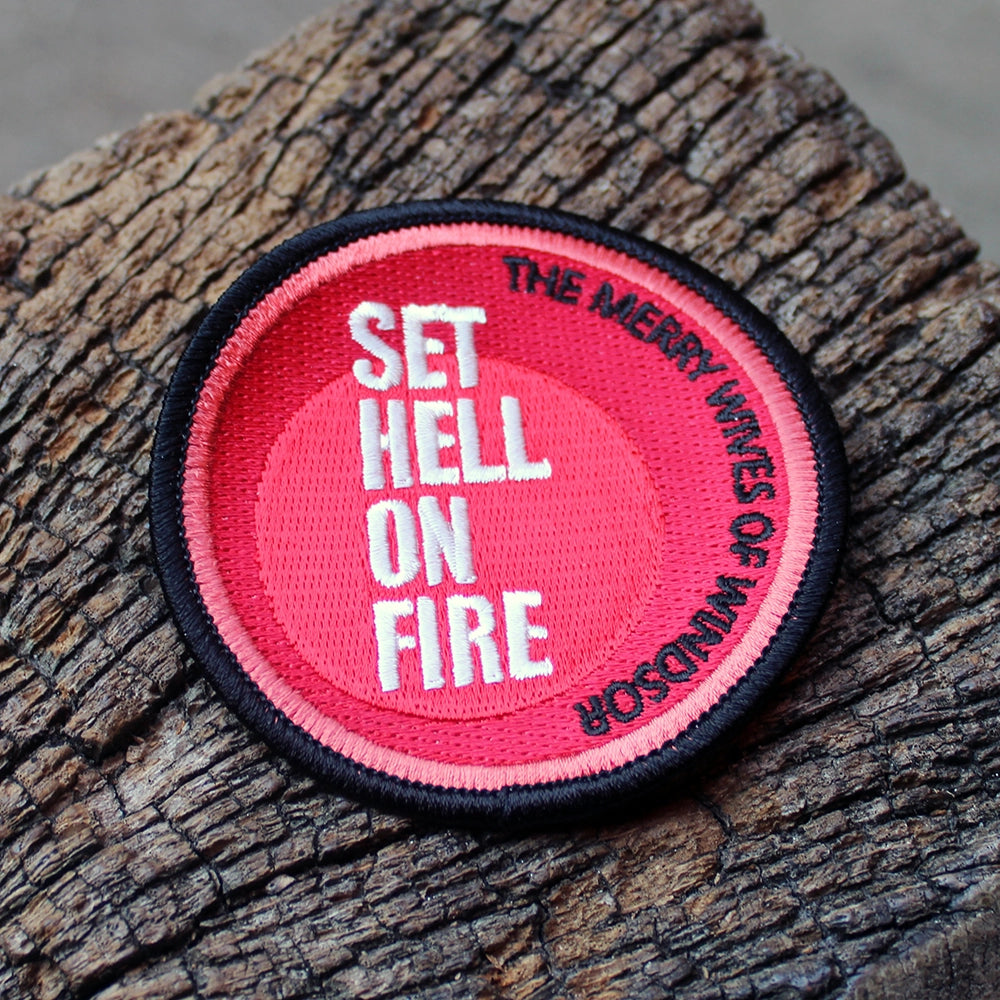 Red and black round embroidered patch on a wooden post
