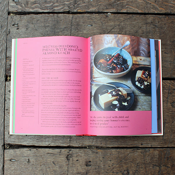 Open cookbook on a wooden surface with a recipe for prunes with roasted almond leach