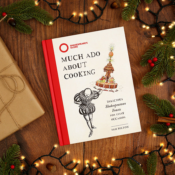 Book titled 'Much Ado About Cooking' on a wooden surface with festive decorations.