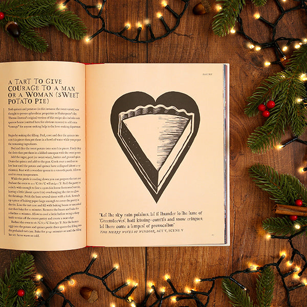 Open book with a heart illustration on a wooden surface with Christmas decorations.