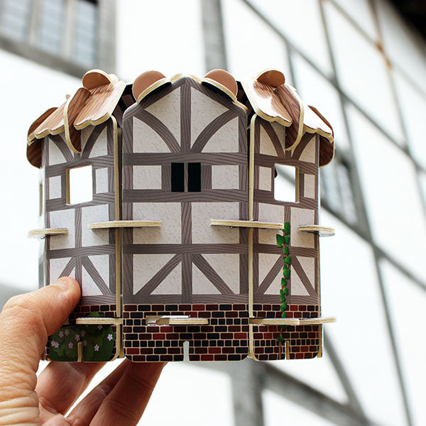 building kit of the Globe Theatre held up in front of the real Globe Theatre