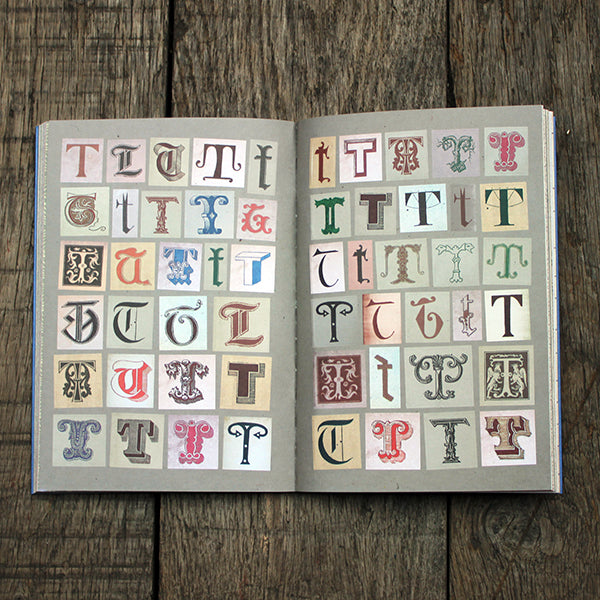 Open book with pages displaying various styled letters stickers on a wooden surface