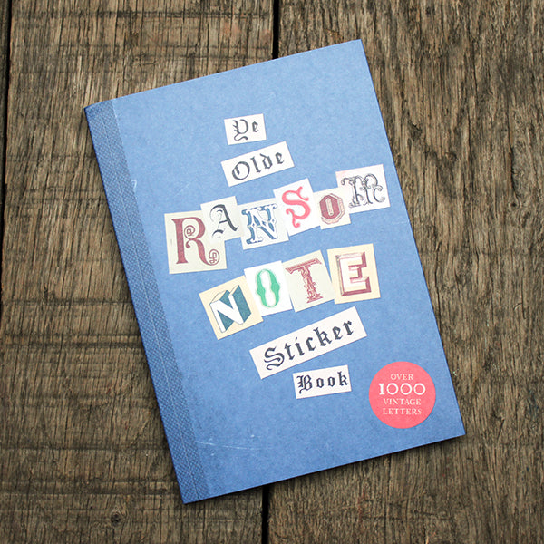 Blue sticker book titled 'Ye Olde Ransome Note' on a wooden surface