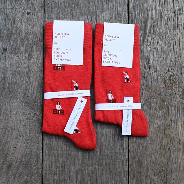 Red cotton blend socks with repeating images of Romeo kneeling and Juliet in her balcony, packaged in white card packaging