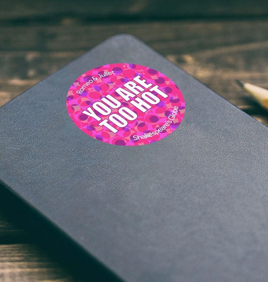 Pink circular sticker with text on a black notebook