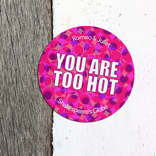 Pink circular sticker with text on a textured surface
