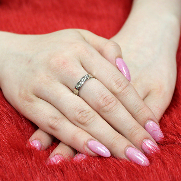 Engraved silver ring on hands which are resting on plush red background